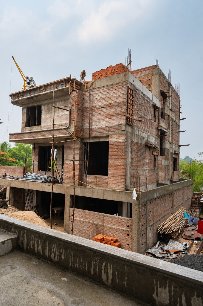 Multi-storey brick and RCC building under construction with scaffolding on site