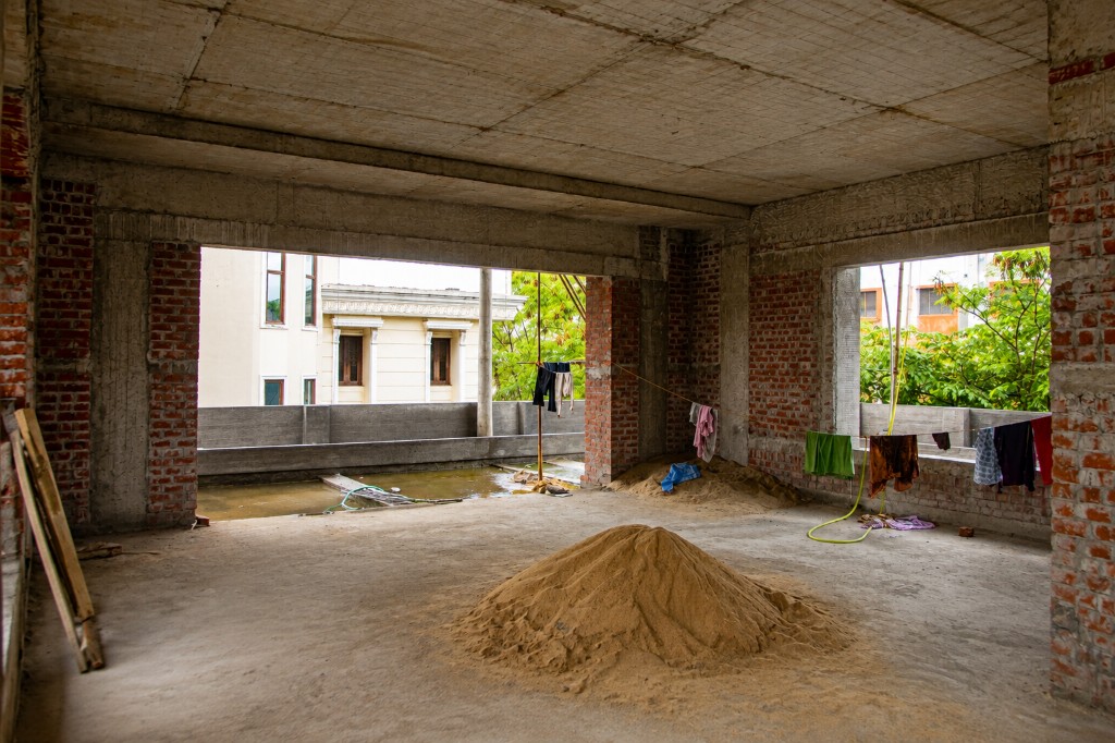 Brick masonry and interior slab preparation with sand piles on construction floor